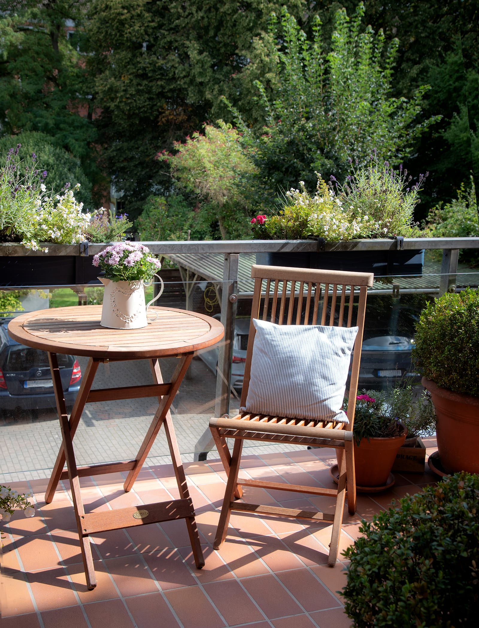 Balkon der Praxis mit Holztisch, Stuhl und Blumenkästen im Grünen